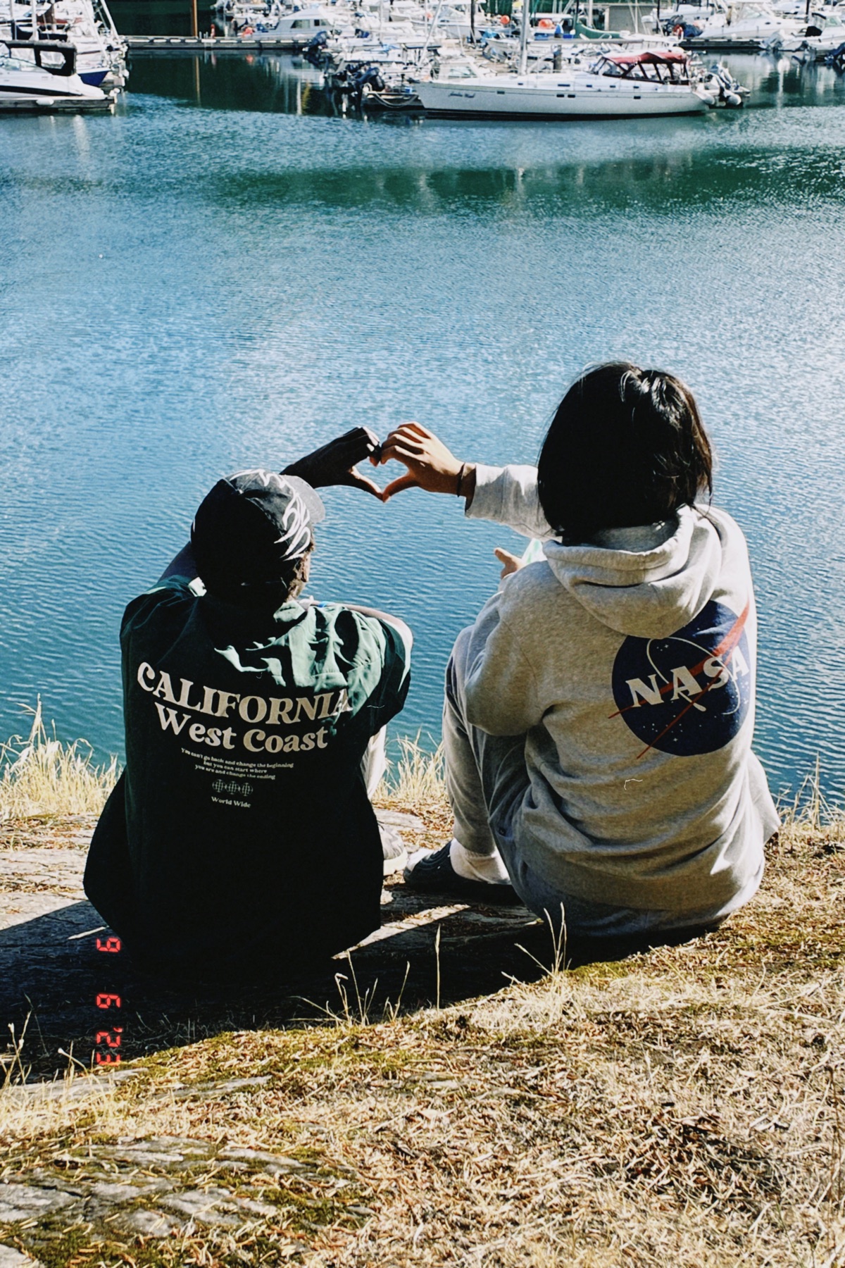 Friends making a heart by the marina